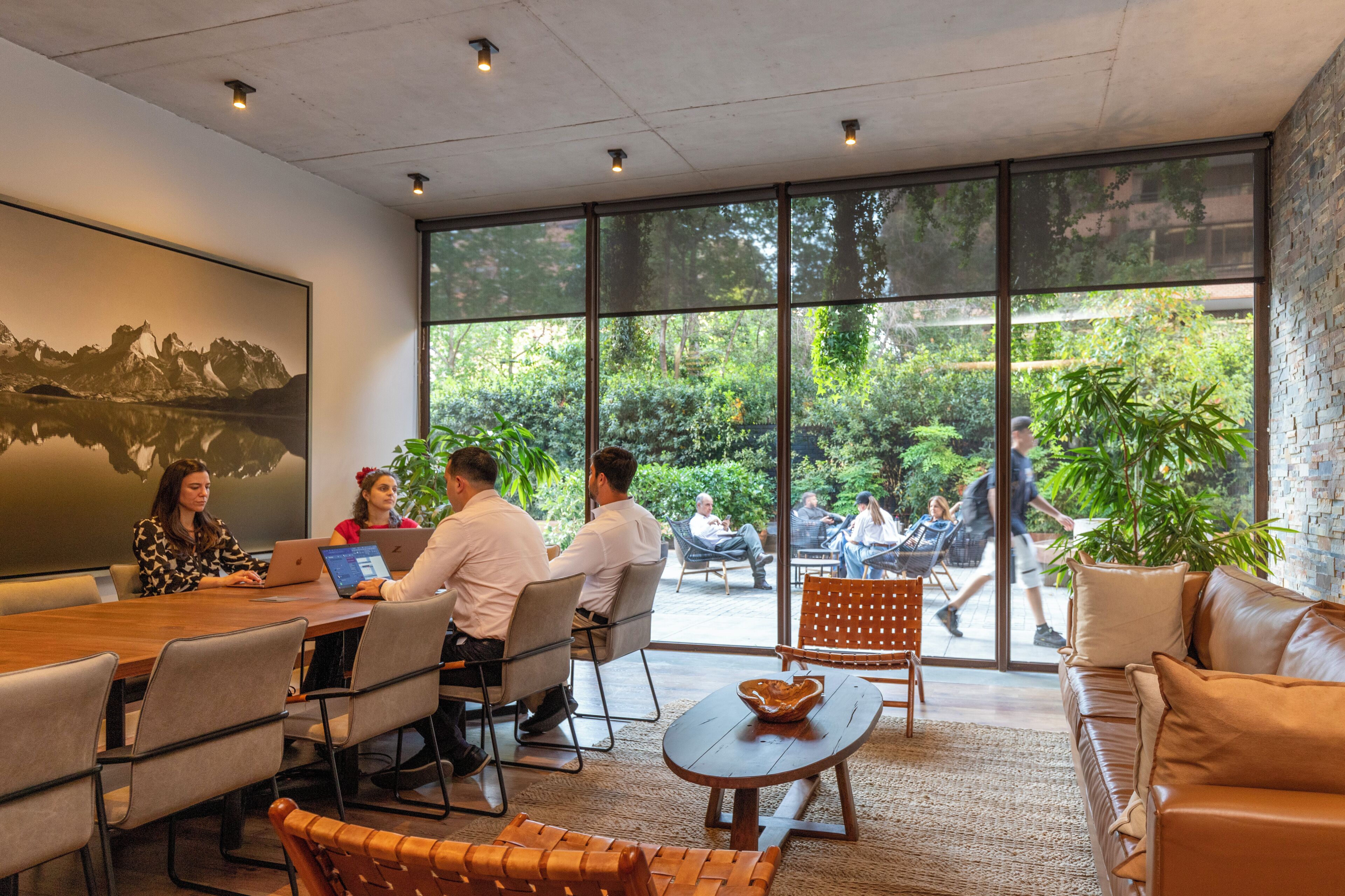 Une salle de réunion moderne dotée de grandes fenêtres, d’une table en bois et de sièges confortables.