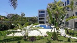 Un hôtel moderne doté d’une piscine, entouré d’une végétation luxuriante et de palmiers.