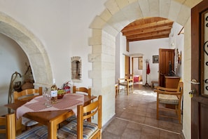 Un coin repas rustique avec une table et des chaises en bois, une nappe à carreaux et un mur en pierre.
