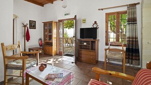 Um quarto aconchegante com móveis de madeira, uma televisão e vista para o exterior.