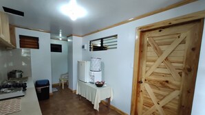 A kitchen with a refrigerator, a water dispenser, and a wooden door. - Log Homes Inspired Unit w/ Wi-Fi and Cable (Baguio)