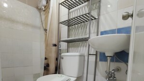 A bathroom with a toilet, a sink, a shower, and a shelf unit. - Log Homes Inspired Unit w/ Wi-Fi and Cable (Baguio)