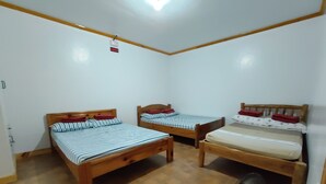 A room with three wooden beds, each with a different mattress and pillow arrangement. There is a ceiling fan on the right side. - Log Homes Inspired Unit w/ Wi-Fi and Cable (Baguio)