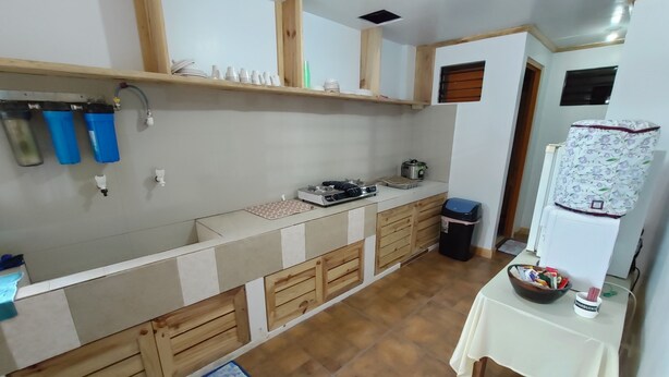 A compact kitchen with a wooden countertop, a sink, and a stove. There is a trash bin and a table with a bowl and a Starbucks cup. - Log Homes Inspired Unit w/ Wi-Fi and Cable (Baguio)