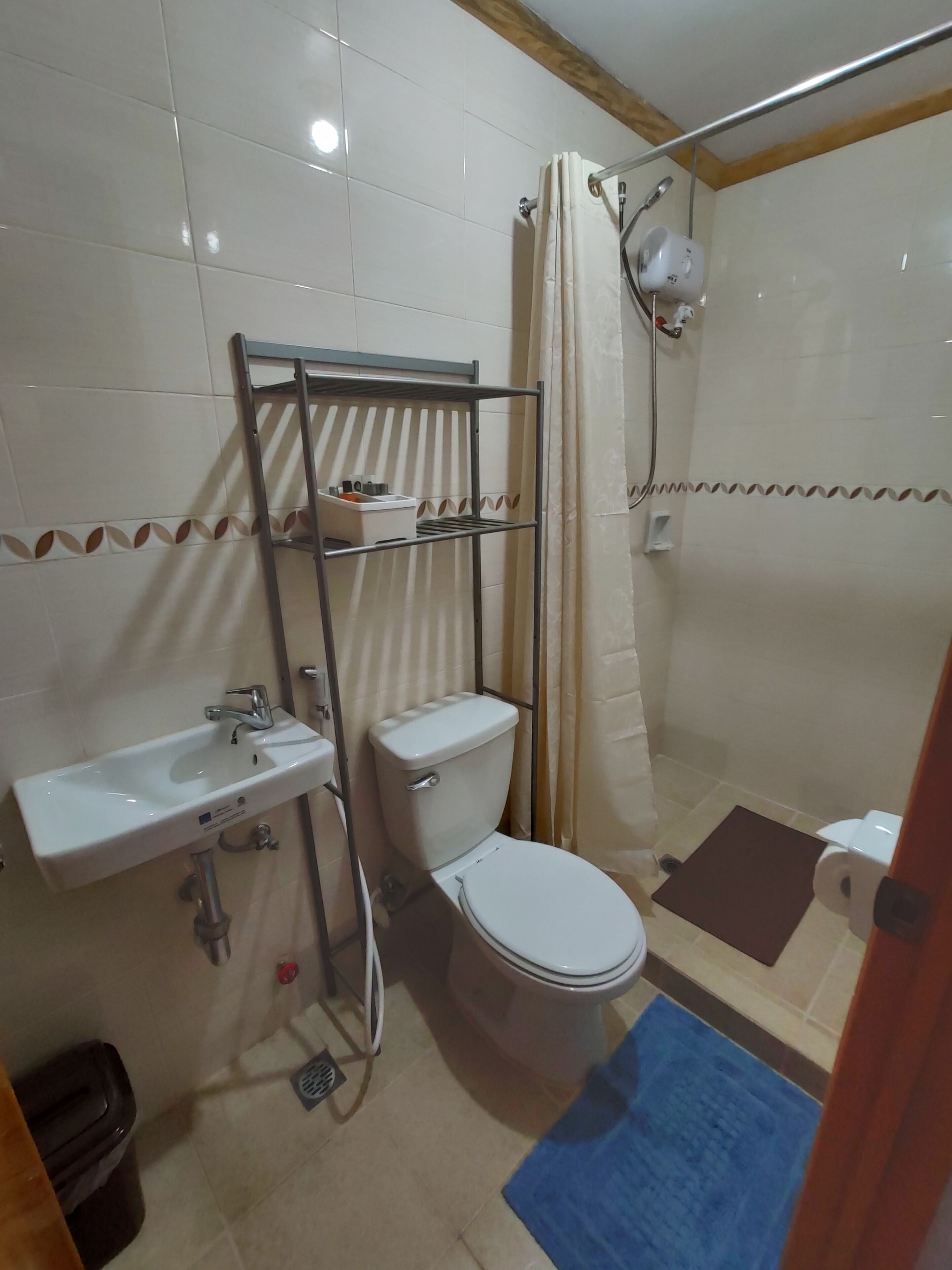 Une salle de bain comprenant des toilettes, un lavabo, une douche et une étagère avec des articles de toilette.