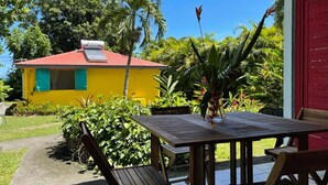 A yellow building with a red roof, surrounded by lush greenery and a clear blue sky. - bungalows Cas'à Willy - Alamanda 3 (Sainte-Rose)
