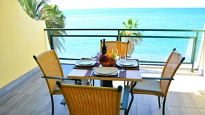 A dining table with chairs and a fruit basket, set against a view of the ocean. - Atlantic view 1 - Apartment with ocean view & pool (Funchal)