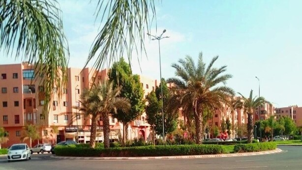 Zona residencial con edificios de varios pisos, palmeras y una glorieta.