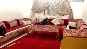 Una sala de estar con un conjunto de sofá, una mesa de centro y una alfombra roja.