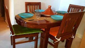 Een eettafel met vier stoelen, een oranje vaas in het midden en blauwe borden.