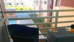 Een balkon met een stoel en een tafeltje met drankjes.