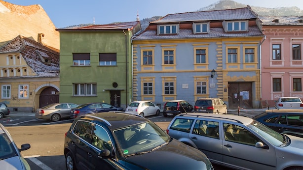 Una vista di strada con auto parcheggiate e edifici dalle architetture diverse.