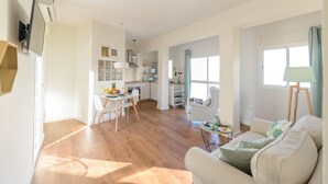 Un vaste espace de vie comprenant une cuisine, un coin repas et un espace salon confortable avec un canapé et des fauteuils.