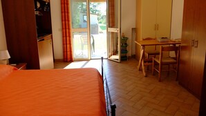 Habitación de hotel con cama, escritorio y silla. Posee un ventanal corredero que da a un espacio exterior.