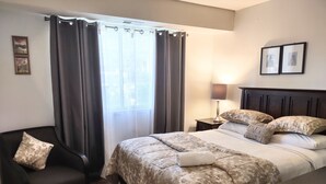 A hotel room with a bed, a chair, a nightstand, and a lamp. - Cozy  2bdr. Condo in Central Raleigh (Raleigh)