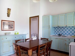 Un coin repas avec une table et des chaises en bois, des meubles de rangement bleu clair, un pare-feu à carreaux et un tableau encadré au mur.