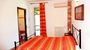 A bedroom with a bed, a radiator, a door, and a wall-mounted picture.
