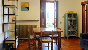 Ein Essbereich mit Holztisch und -stühlen, einem Heizkörper, einem Bücherregal und Blick durch eine Tür.