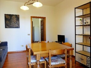 A dining area with a wooden table and chairs, a bookshelf, and a framed artwork on the wall.