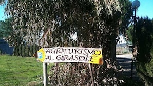 Un panneau indiquant « Agriturismo al Girasole », avec un symbole représentant un parking.