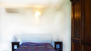 Ein Schlafzimmer mit einem Bett, zwei Nachttischen, einem Kleiderschrank und einer Wandleuchte.