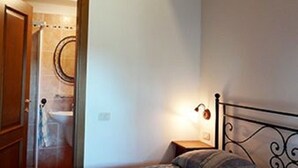 Ein Schlafzimmer mit einem Bett, einem Nachttisch und einer Tür zu einem Badezimmer.