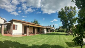 Ein Haus mit Terrasse und einem gepflegten Rasen.