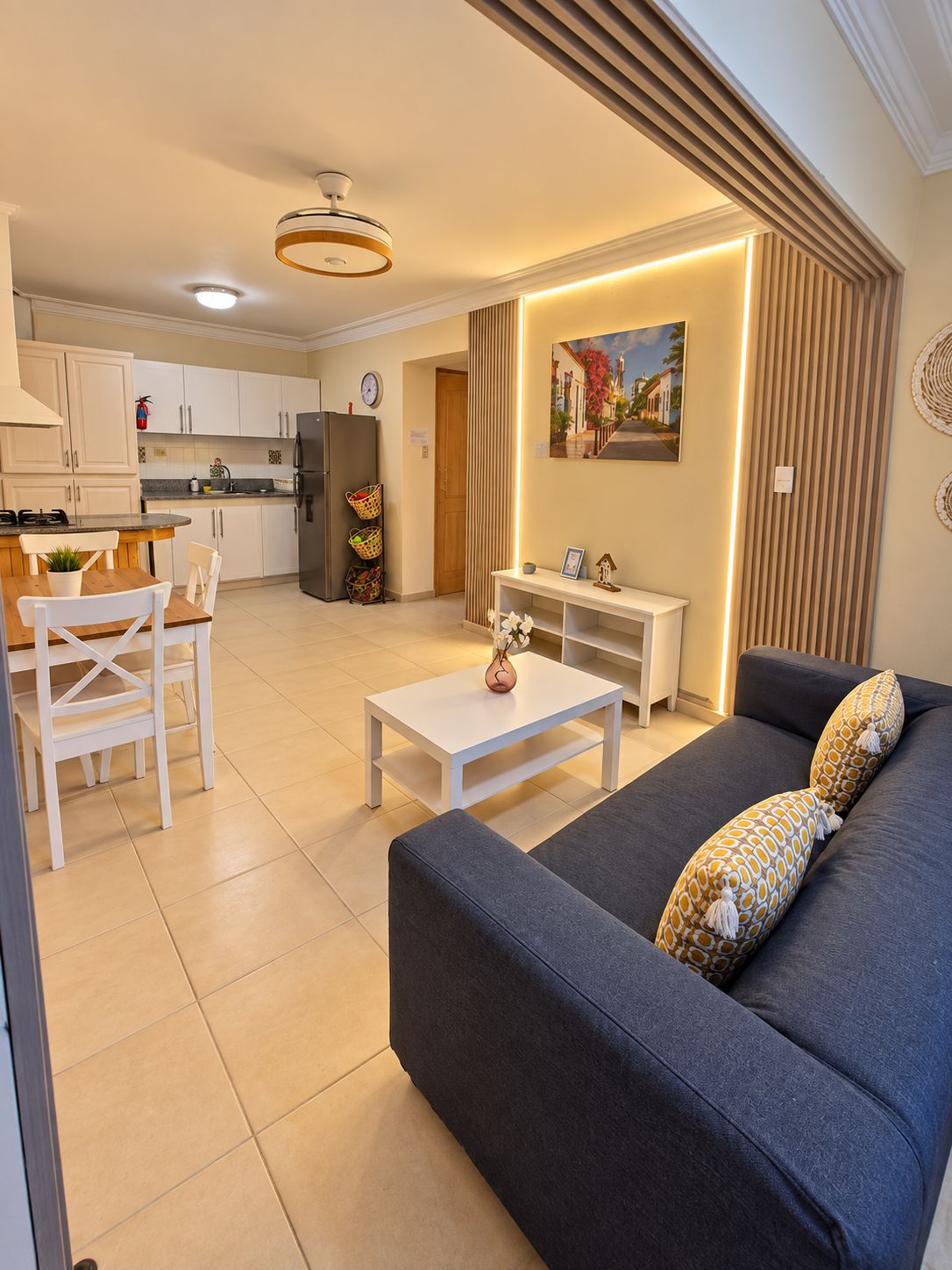 A modern living room with a sofa, a dining area with chairs, a kitchen with cabinets, and a dining table.