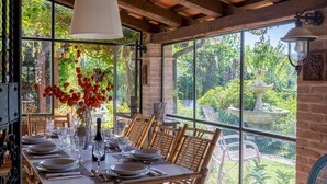 Zona pranzo con tavolo imbandito per sei persone, ampie finestre e vista su un giardino.