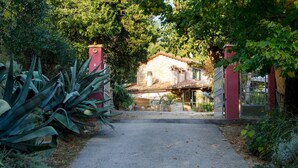 Un vialetto conduce a una casa con facciata in mattoni, tetto in tegole e un camino ben visibile.