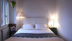A bedroom with a bed, two bedside lamps, a window, and a radiator. - Casa Sofia in the heart of Venice (Venezia)