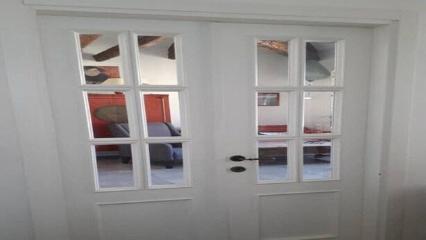 A white door with a glass panel, revealing a room with a bed and a red wall. - Casa Sofia in the heart of Venice (Venezia)