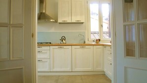 A kitchen with white cabinets, a stainless steel range hood, and a window providing natural light. - Casa Sofia in the heart of Venice (Venezia)