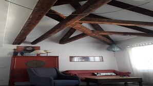 A room with exposed wooden beams, a red cabinet, a blue armchair, a red sofa, and a small table. - Casa Sofia in the heart of Venice (Venezia)