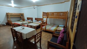 Une chambre de dortoir avec des lits superposés, une table à manger et des chaises.