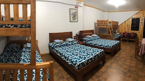 Une chambre de dortoir avec des lits superposés, un ventilateur et un tableau encadré au mur.