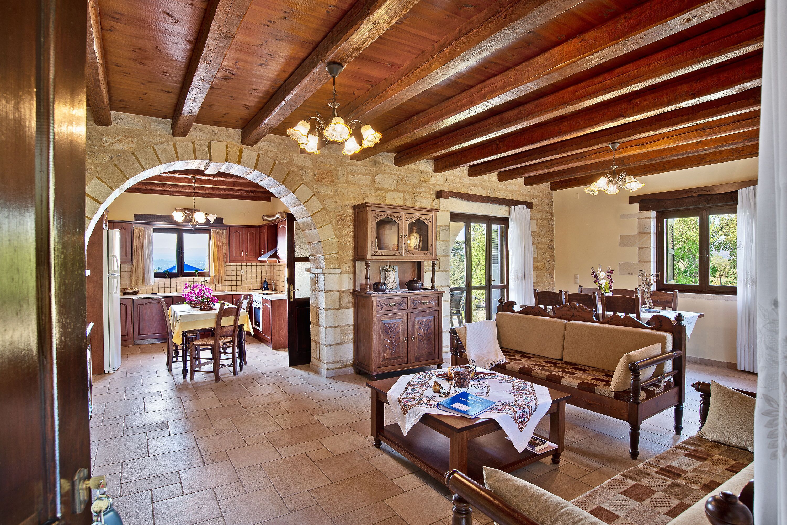 A spacious living area with a wooden ceiling, stone walls, and a dining area with a table and chairs.