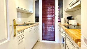A narrow kitchen with white cabinets, a wooden countertop, a coffee maker, and a toaster. - Pool view private terrace ground floor Mijas Costa with barbecue by Solrentspain (Mijas Costa)