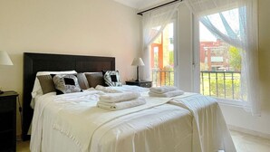 A bedroom with a large bed, a nightstand, a lamp, and a view of the outside. - Pool view private terrace ground floor Mijas Costa with barbecue by Solrentspain (Mijas Costa)
