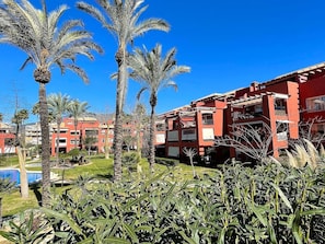 A hotel with red exterior walls, palm trees, and a clear blue sky.