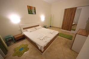 A neatly arranged bedroom with a bed, bedside table, and a green mat on the floor. - Menada Negresco Apartments (Elenite)