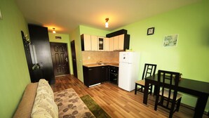 Un espacio habitable compacto con kitchenette, zona de comedor y sofá.