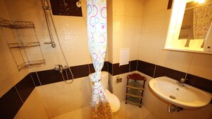 Un baño con inodoro, lavamanos, ducha y espejo.