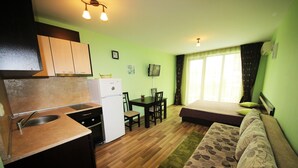 Una habitación compacta con kitchenette, comedor y cama.