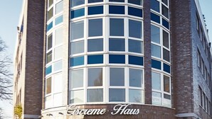Ein Eckgebäude mit einer gebogenen Fassade, großen Fenstern und einem Schild mit der Aufschrift 'Ciscreme Haus'.