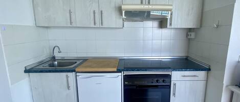 A compact kitchen with white cabinets, a built-in oven, a dishwasher, and a sink.