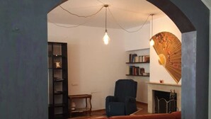 Un salon chaleureux avec un canapé rouge, un fauteuil bleu et une bibliothèque.