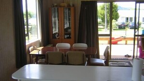 A compact room with a dining table, four chairs, a cabinet, and a large window.