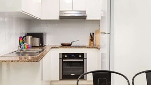 Une cuisine moderne avec des armoires blanches, une hotte de cuisinière en acier inoxydable, un four à micro-ondes, un grille-pain et un four.