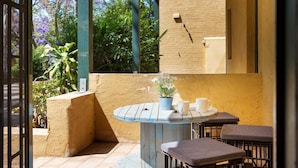 Une terrasse avec une table ronde, deux chaises et un pot de fleurs.